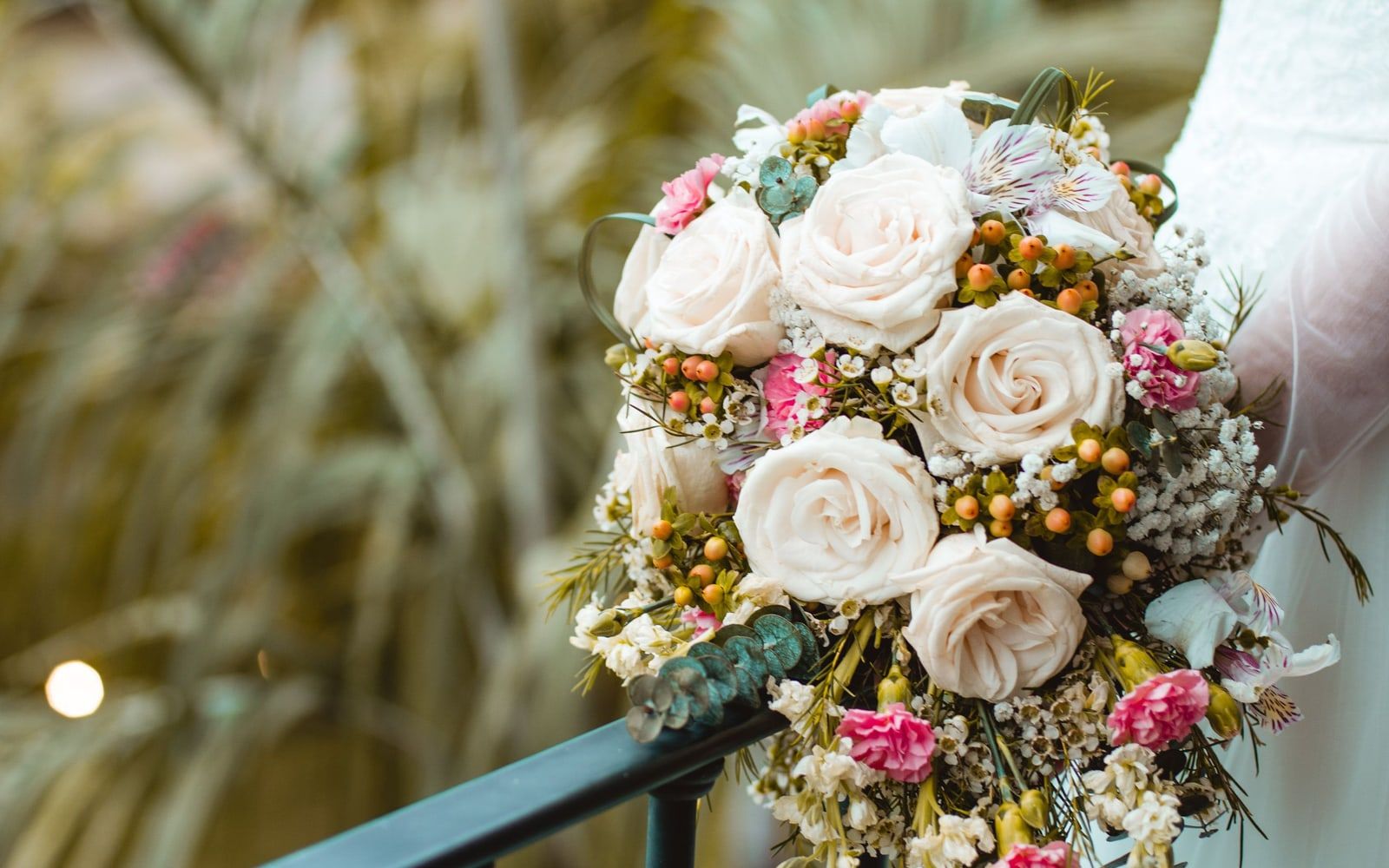 Brautstrauß aus weißen und rosa Rosen vor einem weißen Kleid