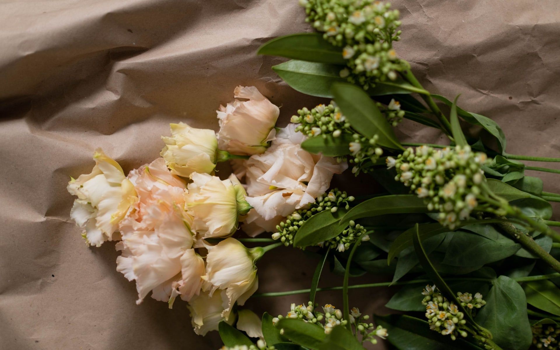 Helle Lisianthus-Blüten mit Grün auf braunem Papier